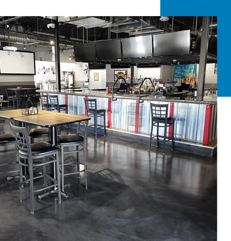 Sleek charcoal commercial epoxy flooring with a satin finish in a modern sports bar and restaurant interior.